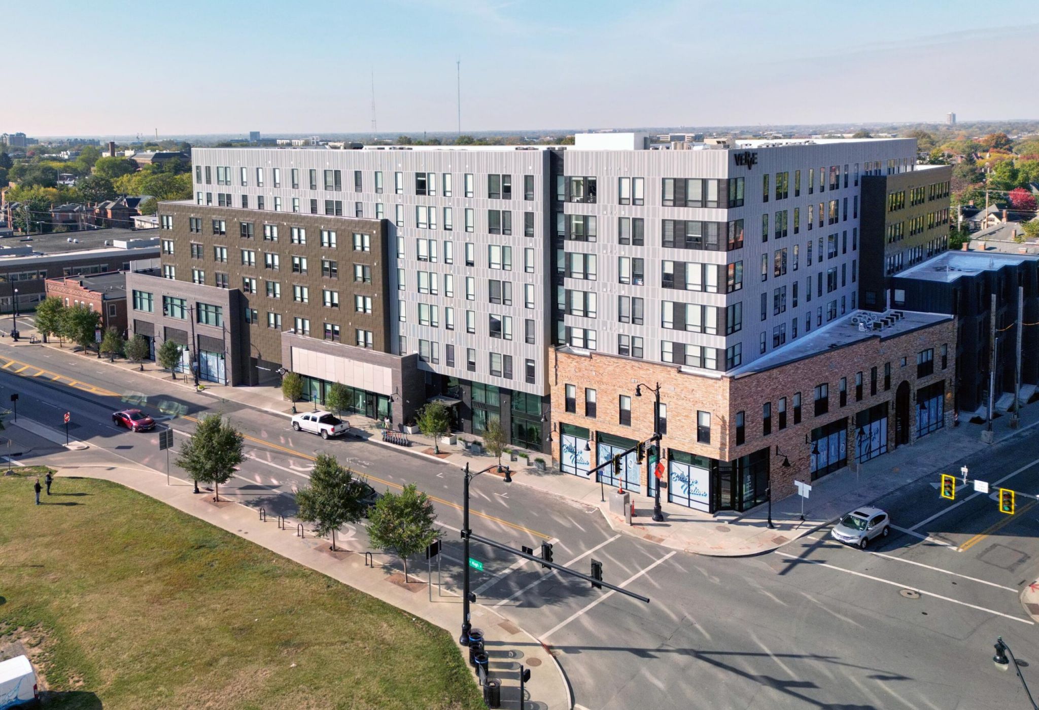 Aerial view of the VERVE Columbus, a modern multi-story apartment building complex at a street intersection on a sunny day.