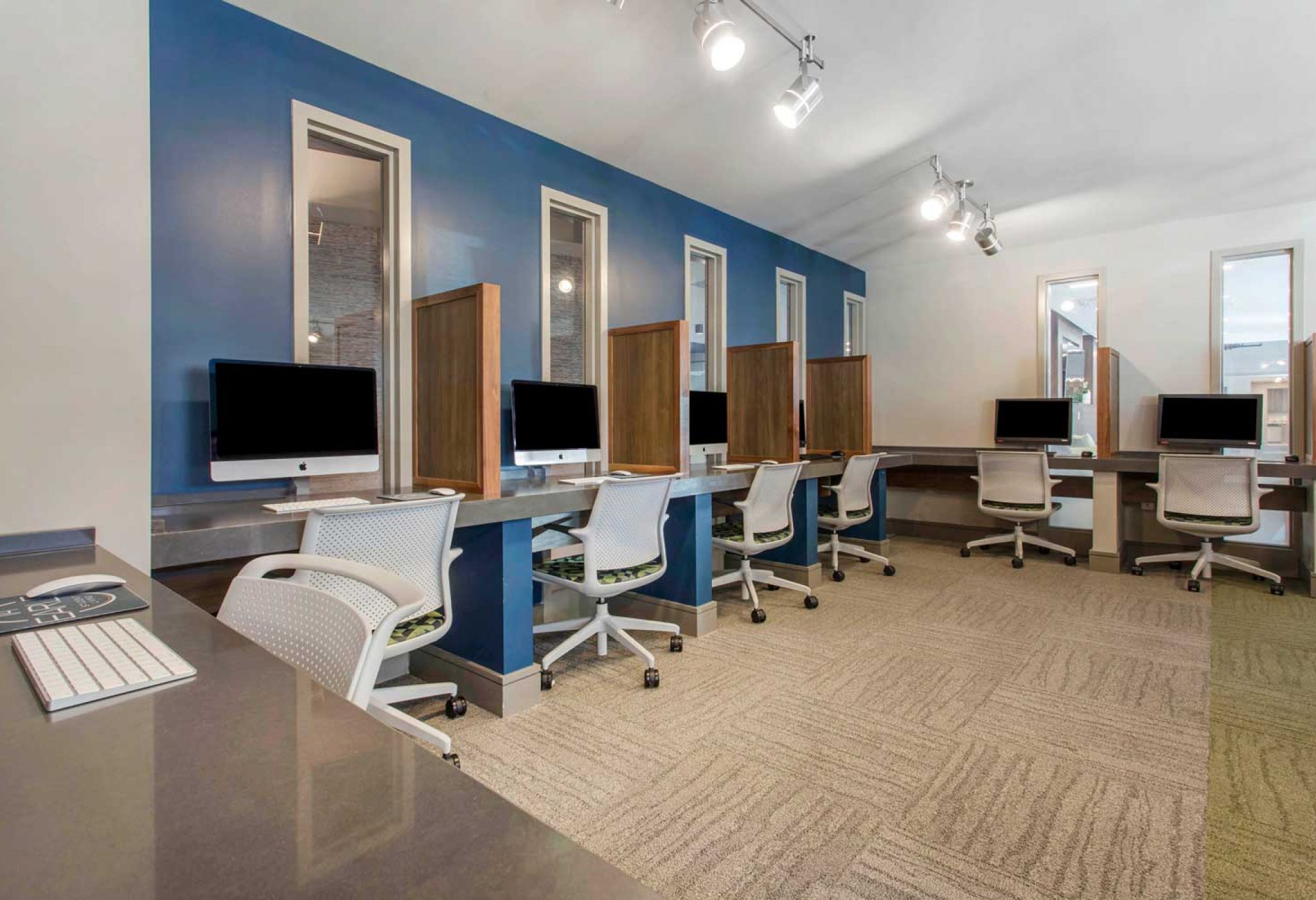 A modern computer lab at 114 Earle features individual workstations, each equipped with a computer, surrounded by blue and white walls.