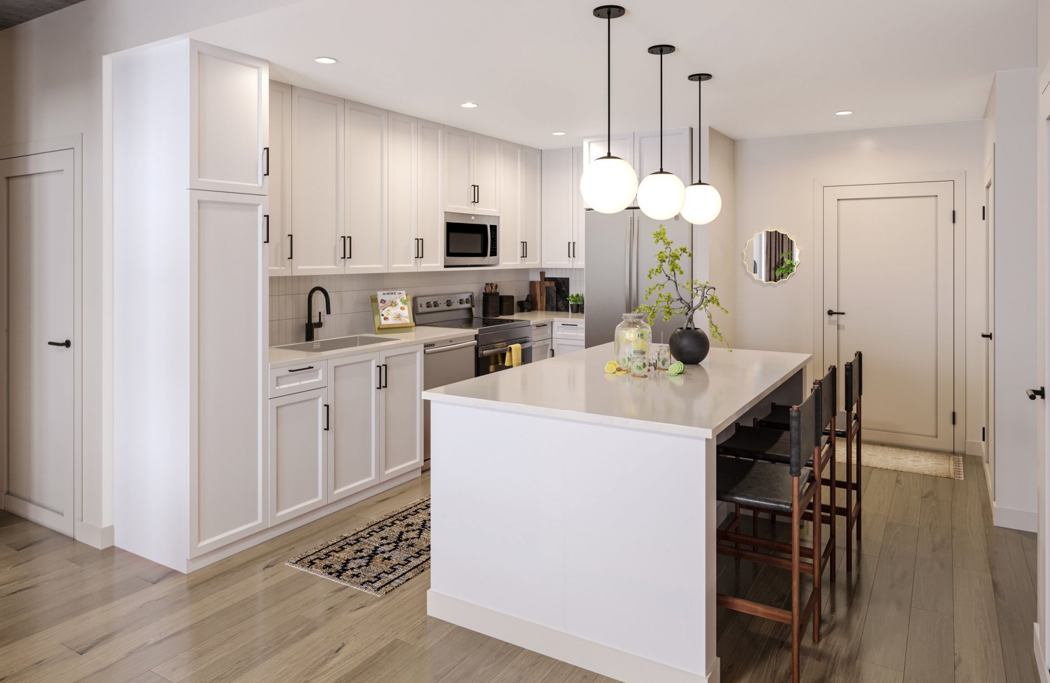 A modern kitchen features white cabinetry, stainless steel appliances, and a large island with a white countertop. Three round pendant lights hang above the island, with a vase and plants as decor. Wooden bar stools are tucked in, and light wood flooring completes the look.