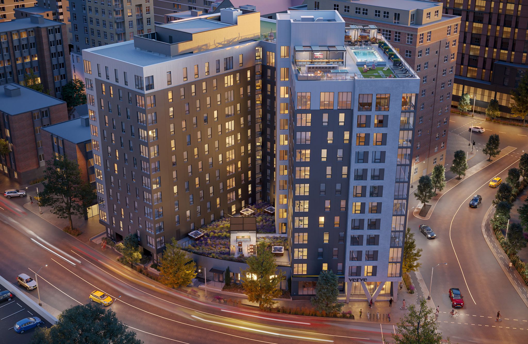 A bird's-eye view of VERVE Madison, a modern high-rise apartment building in an urban area at dusk. The building features a rooftop pool and terrace, with city streets and other high-rise buildings surrounding it. Traffic and city lights add vibrancy to the scene.