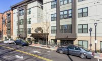 Modern apartment building at 114 Earle features large windows, multiple floors, and cars parked along the street in front.