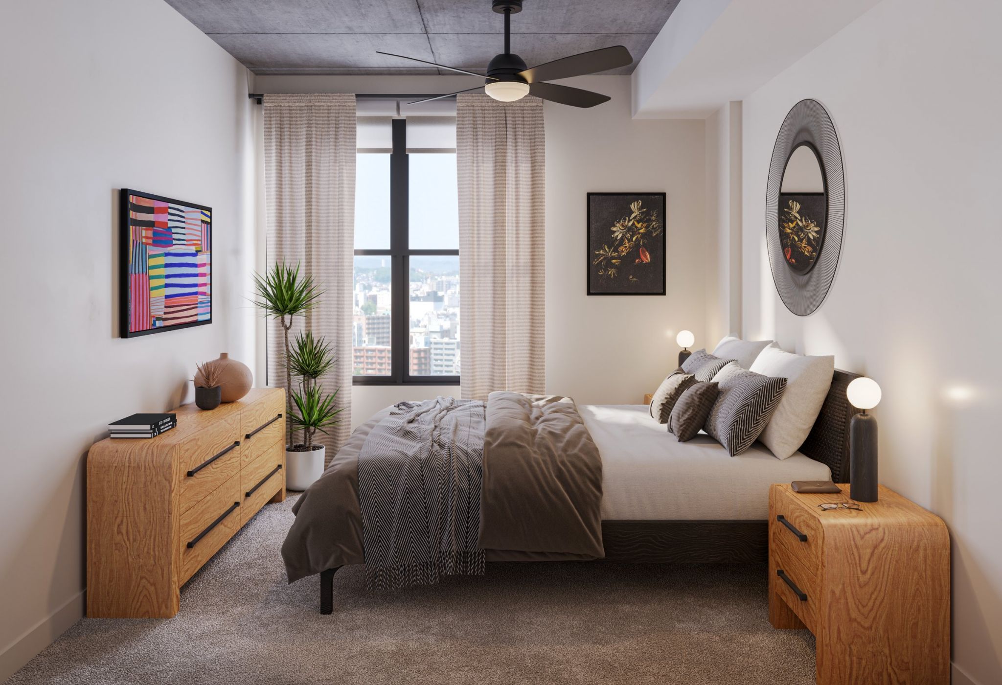 A modern bedroom features a large window with light-colored curtains, a ceiling fan, a bed with pillows and a gray comforter, wooden side tables with lamps, a wooden dresser, two framed artworks, a round wall mirror, and potted plants.