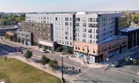 Aerial view of the VERVE Columbus, a modern multi-story apartment building complex at a street intersection on a sunny day.