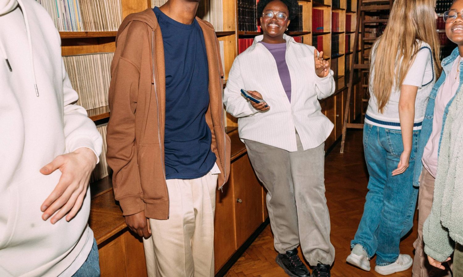 Subtext Living: A group of people smiling and chatting in a lively library setting.
